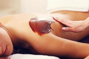 Beautiful woman getting chocolate massage in spa photo