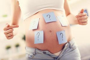 Photo of pregnant woman with question marks on belly