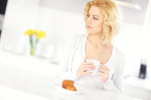 Young woman drinking coffee in the kitchen photo