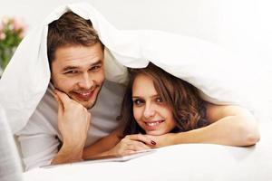 Happy couple resting in bedroom with tablet photo