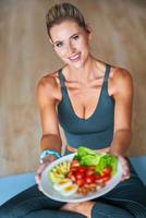 Adult woman eating healthy lunch and sitting on yoga mat photo