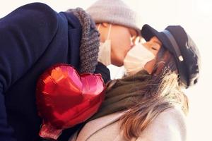 Happy couple celebrating Valentines Day in masks during covid-19 pandemic photo