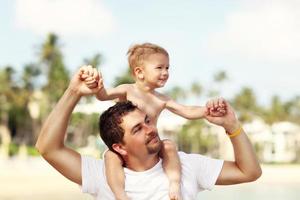 Father having fun on the beach with his little son photo