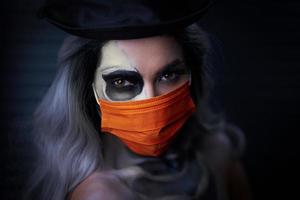 Spooky portrait of woman in halloween gotic makeup wearing protective mask photo