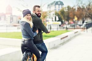 pareja joven montando en bicicleta y divirtiéndose en la ciudad foto