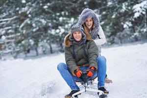 Couple having fun with sledge on snow in winter photo