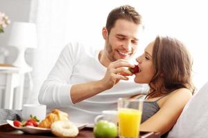 pareja joven desayunando en la cama foto