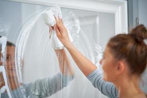 Picture of yound woman cleaning mirror window photo