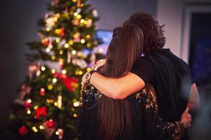 Adult couple hugging over Christmas tree photo