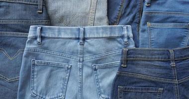 Various blue shades and sizes of pairs of denim jeans back side photo