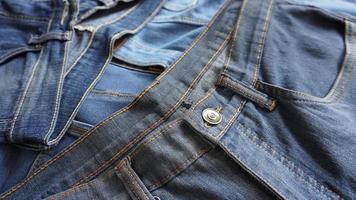 Pile of vintage denim jeans close up photo