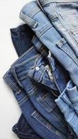 Stack of pairs of denim jeans of various blue shades and sizes photo