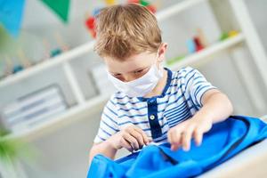 Adorable little boy in kindergarten with mask on due to coronavirus pandemic photo