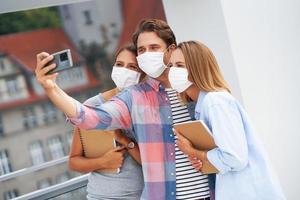 un par de estudiantes con máscaras mientras se toman selfies en el campus foto