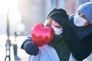 Happy couple celebrating Valentines Day in masks during covid-19 pandemic photo