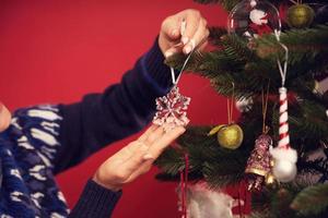 Adult woman decorating Christmas tree over red background photo