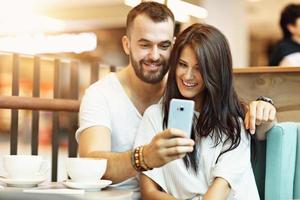 Romantic couple dating in cafe and using smartphone photo