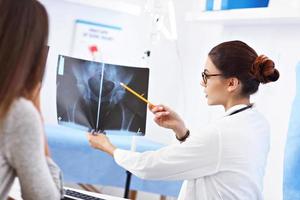 mujer adulta discutiendo los resultados de rayos X durante la visita al consultorio de una doctora foto