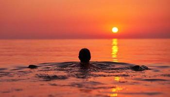 Young woman swimming in the sea on sunrise photo