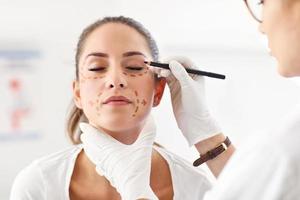 Plastic surgeon making marks on patient's body photo