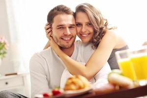 Young couple eating breakfast in bed photo