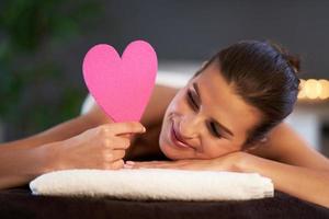 Relaxed woman waiting for a back massage and holding heart photo