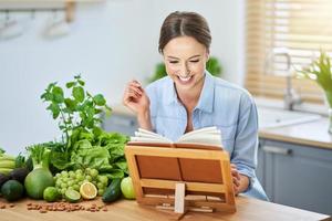 mujer adulta sana con comida verde en la cocina foto