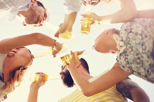 Group of young people cheering and having fun outdoors with drinks photo