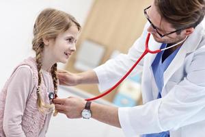 Little girl in clinic having a checkup with pediatrician photo