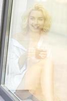 mujer bonita joven bebiendo café en la ventana foto