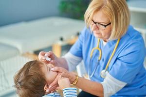médico pediatra que examina a los niños pequeños en la clínica foto