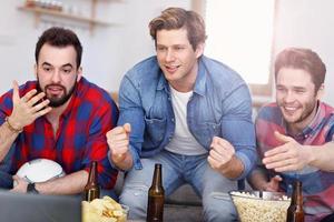 Happy male friends cheering and watching sports on tv photo