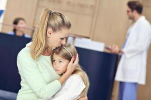 Little girl is crying while with her mother at a doctor on consultation photo