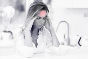 joven mujer triste que sufre de dolor de cabeza en la cocina foto