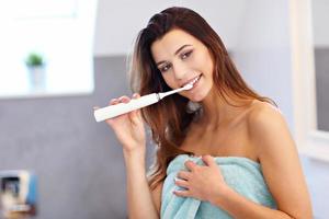 mujer joven lavando los dientes en el baño por la mañana foto