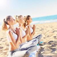 Group of women practising yoga on the beach photo