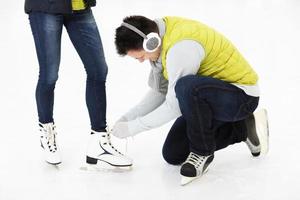 joven atando patines en una pista de patinaje foto