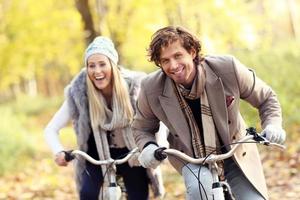 Happy couple on bikes in forest during fall time photo