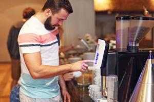 hombre atractivo que usa la máquina de café en el hotel foto