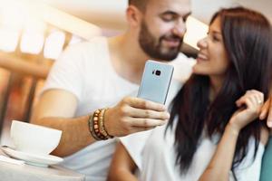 Romantic couple dating in cafe and using smartphone photo