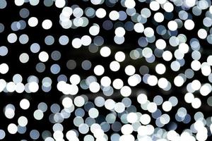 Bokeh white lights on black background, defocused and blurred many round light on background photo
