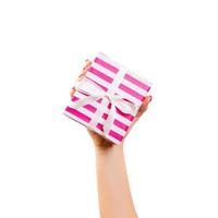 Woman hands give wrapped Christmas or other holiday handmade present in pink paper with white ribbon. Isolated on white background, top view. thanksgiving Gift box concept photo