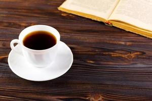 Still life with cup of coffee and book on grunge wood table in vintage style photo