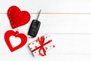 Top view of a present for Valentine's Day on wooden background. Car key, gift box and heart with copy space. Surprise concept for a holiday photo