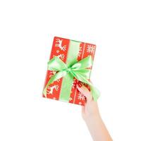 Woman hands give wrapped Christmas or other holiday handmade present in red paper with green ribbon. Isolated on white background, top view. thanksgiving Gift box concept photo