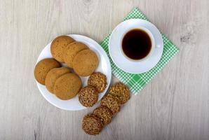 Cup of coffee wiyh pile of various shortbread and oat cookies with cereals on wooden background. photo