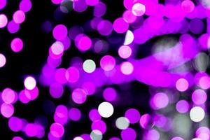 Unfocused abstract purple bokeh on black background. defocused and blurred many round light photo