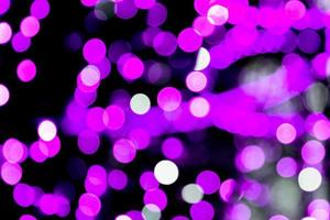 Unfocused abstract purple bokeh on black background. defocused and blurred many round light photo