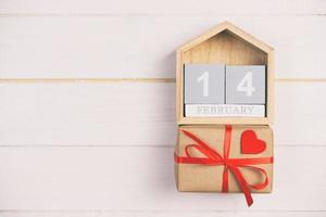 Cube calendar with red heart and gift box on wooden toned, vintage table with copy space. 14 February concept photo