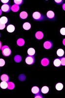 Unfocused abstract purple bokeh on black background. defocused and blurred many round light photo